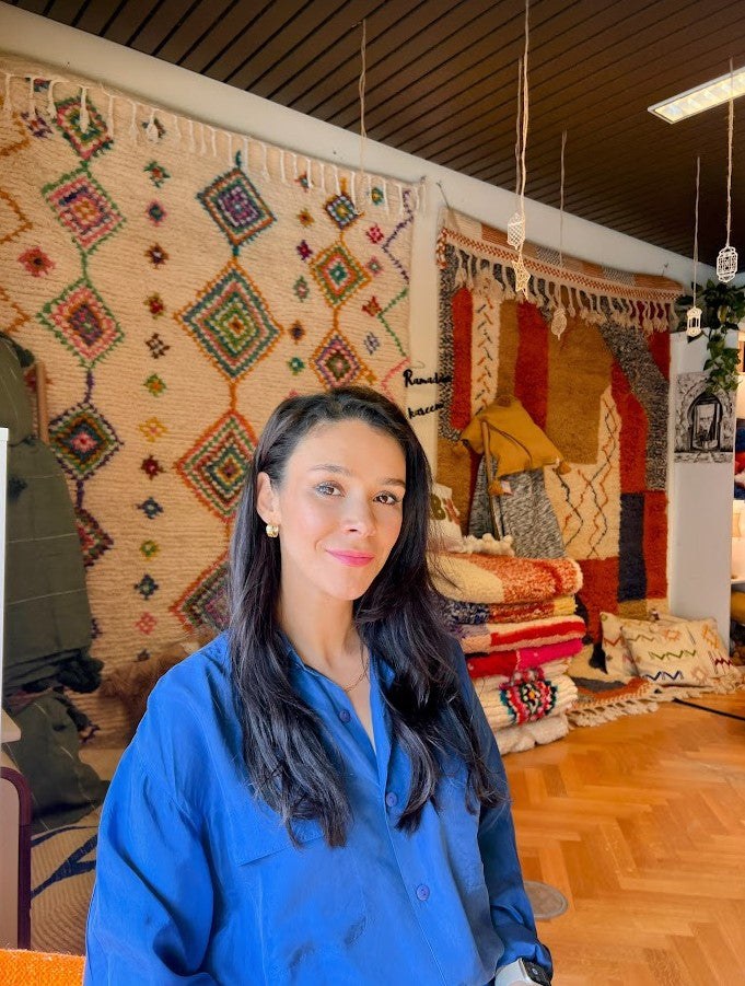 Nadia, fondatrice de Maison Mazhar, devant une sélection de tapis berbères.